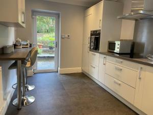 a kitchen with white cabinets and a counter with a microwave at Ground floor garden apartment in Newark-on-Trent
