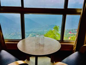 two glasses sitting on a table in front of a window at Staynest Regency Pelling in Pelling