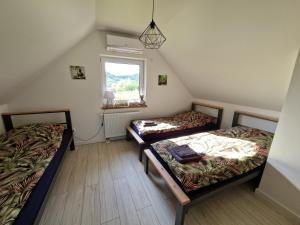 PaszynにあるDomek w Paszynie - Sauna i Gorąca baliaのベッド2台と窓が備わる屋根裏部屋です。