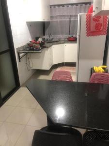 a small kitchen with a black table and chairs at Quarto em Alphaville Barueri SP in Barueri