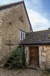 an old brick building with a wooden door and a cross at The Old Library in Castle Combe