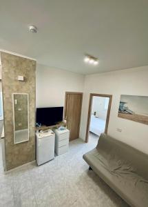 a room with a bed and a tv and a couch at SeaSide BnB -Elegante Appartamento- FRONTE MARE in Porto San Giorgio