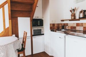 a small kitchen with white cabinets and a microwave at Penty au Ménec in Carnac