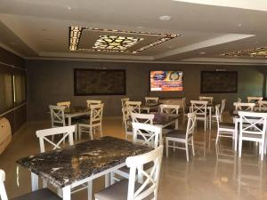 a dining room with tables and white chairs at Grand Plaza 6 Octobar in Qaryat ash Shamālī
