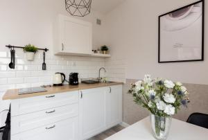 a kitchen with white cabinets and a vase of flowers on a table at Palm Aparts Gdańsk in Gdańsk
