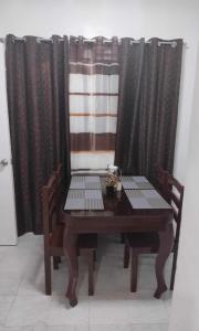 einen Esstisch und Stühle vor den Vorhängen in der Unterkunft DAVAO Transient House 2 in Davao City