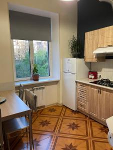 a kitchen with a table and a white refrigerator at Freddies apartment in Kyiv
