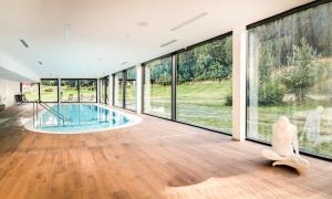 a large room with a swimming pool and large windows at Cihelny Golf & Wellness Resort in Karlovy Vary