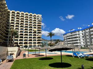 ein Pool mit Sonnenschirmen und Stühlen sowie ein Resort in der Unterkunft Aloha Playa España in Benalmádena