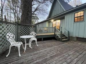 2 Stühle und ein Tisch auf einer Holzterrasse in der Unterkunft Doc's Cottage - A-Frame in Piggott, AR 