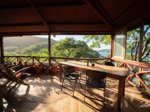een houten tafel en stoelen op een veranda met uitzicht bij 300m to beach/center: 2 bedr-2 bath & great views! in San Juan del Sur