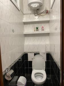 La salle de bains est pourvue de toilettes blanches et de carrelage noir. dans l'établissement Freddies apartment, à Kiev