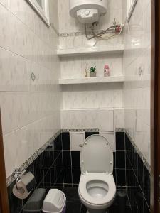 a bathroom with a white toilet and black tiles at Freddies apartment in Kyiv +15 photos