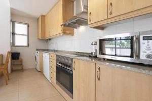 a kitchen with wooden cabinets and stainless steel appliances at Apartamento Terraza Bora Bora in El Campello