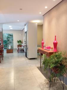 un vestíbulo con una mesa con jarrones rojos. en Mariachis Hotel en Passos