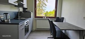 une cuisine avec une table et une cuisinière ainsi qu'une fenêtre dans l'établissement Gästehaus Orchidee, à Hoya