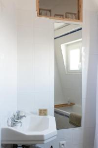 uma casa de banho branca com um lavatório e um espelho em La Favorite - app plage à Mers em Mers-les-Bains