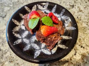 a black plate with a piece of chocolate dessert with strawberries at Tree Aloe Guest House in Mokopane