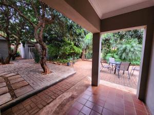 a patio with a tree and a table and chairs at Tree Aloe Guest House in Mokopane