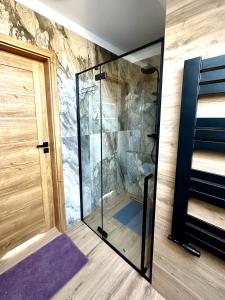 a shower with a glass door in a room at Domek SAMI SWOI in Zawoja +35 photos