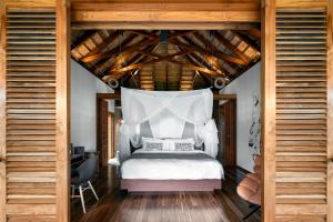 a bedroom with a white bed with a wooden ceiling at Zuri Zanzibar in Kendwa