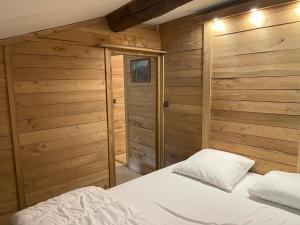 - une chambre avec des murs en bois et un lit avec des draps blancs dans l'établissement Grange rénovée, Pyrénées Ariégeoises, Gîte haute Ariège, à Auzat