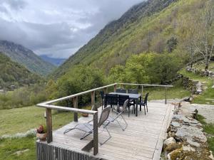 une terrasse en bois avec une table et des chaises. dans l'établissement Grange rénovée, Pyrénées Ariégeoises, Gîte haute Ariège, à Auzat