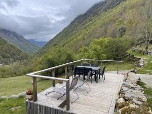 eine Holzterrasse mit einem Tisch und Stühlen darauf in der Unterkunft Grange rénovée, Pyrénées Ariégeoises, Gîte haute Ariège in Auzat