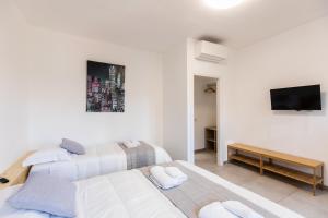 duas camas em um quarto branco com uma tv em CityHouse Fm StationRho Fair Near center em Rho