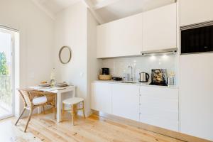 una cucina con armadi bianchi, tavolo e sedia di Porto Downtown Studio with Balcony a Porto