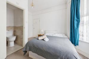 a white bedroom with a bed and a toilet at Calderon Road in London