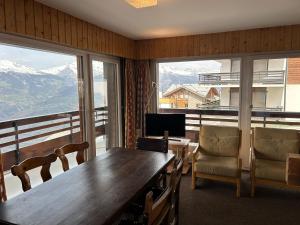 a dining room with a table and chairs and windows at Diablerets SKI LIFT & MOUNTAIN apartments in Veysonnaz