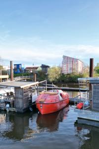 un barco rojo está atracado en un muelle en Ausgebautes Freifallrettungsboot KNUTSCHKUGEL, en Hamburgo