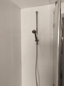 La salle de bains est pourvue d'une douche et de murs blancs. dans l'établissement Cosy Corner, à Lommel