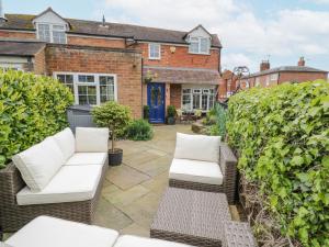 un patio con 2 sofás blancos frente a una casa en Jubilee Cottage en Stratford-upon-Avon