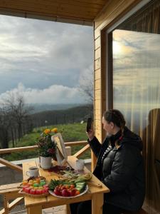 a woman taking a picture of a table of food at Arkhilo's cottage in Dedoplis Tskaro