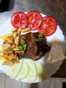 a plate of food with steak and french fries and tomatoes at Ethno village Molitva in Družiniće