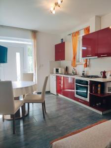 cocina con armarios rojos, mesa y sillas en Siesta Apartments, en Šibenik