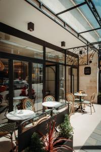 a patio with tables and chairs and windows at In Town Boutique HOTEL in Pristina