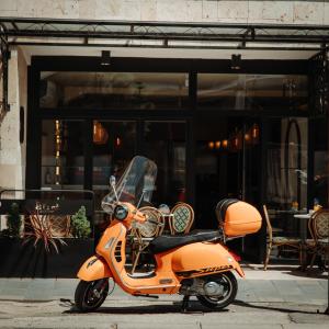 een oranje scooter geparkeerd voor een gebouw bij In Town Boutique HOTEL in Pristina