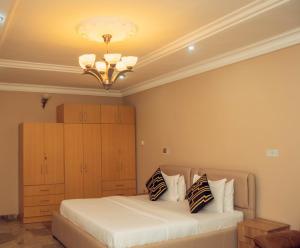 1 dormitorio con cama y lámpara de araña en J's Place Hotel, en Abuja