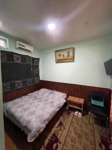 um pequeno quarto com uma cama e uma mesa em Sohil boyi em Fergana