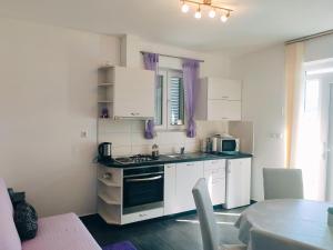 a kitchen with white cabinets and a stove top oven at Siesta Apartments in Šibenik