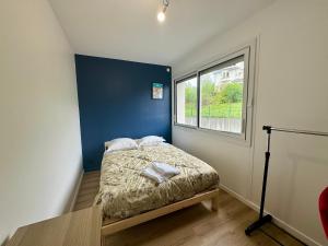 ein Schlafzimmer mit einem Bett mit blauer Wand und einem Fenster in der Unterkunft F3 charmant neuf et équipé avec balcon "Wailly" in Clermont-Ferrand
