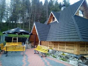 a house with two benches and an umbrella at Willa Sport in Zakopane