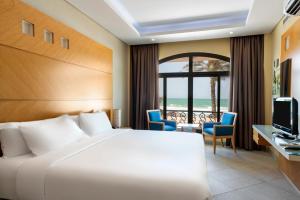 a hotel room with a bed and a television at Occidental Sharjah Grand in Sharjah