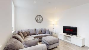 a living room with a couch and a tv at Spacious three bedroom apartment with Valley views in Abertillery