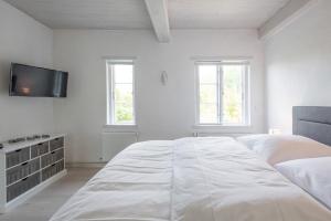 a white bedroom with a large bed and a flat screen tv at FeWo Watt-Lounge zwischen Husum und Nordstrand in Wobbenbüll