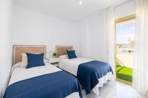 two beds in a room with a window at Avanti Aqua Marina con PARKING GRATIS in Fuengirola