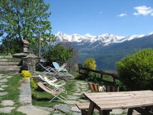 a group of chairs and a picnic table with mountains in the background at Agriturismo Les Ecureuils in Saint-Pierre